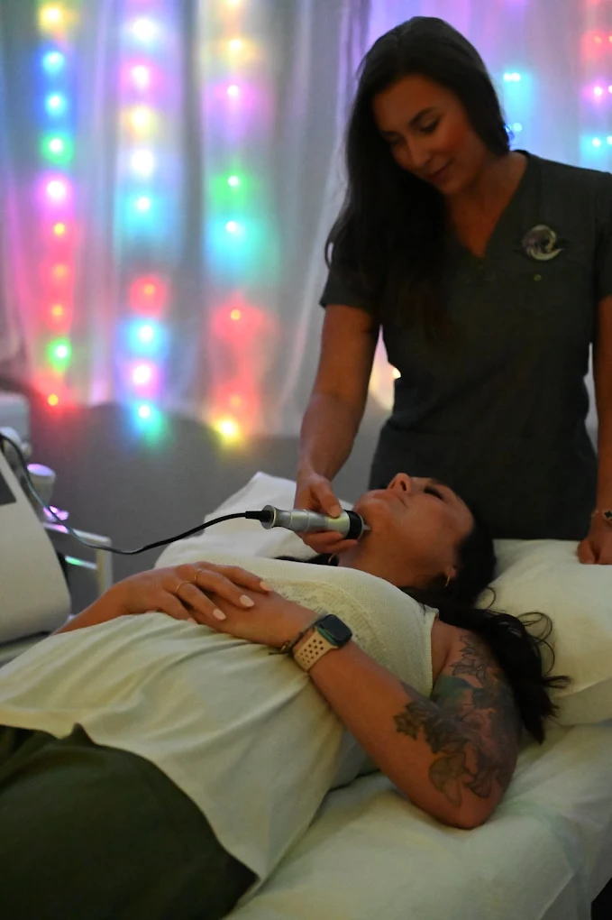Woman receiving non-invasive body sculpting treatment with colorful lights in the background, showcasing personalized care at Superior Sculpting.